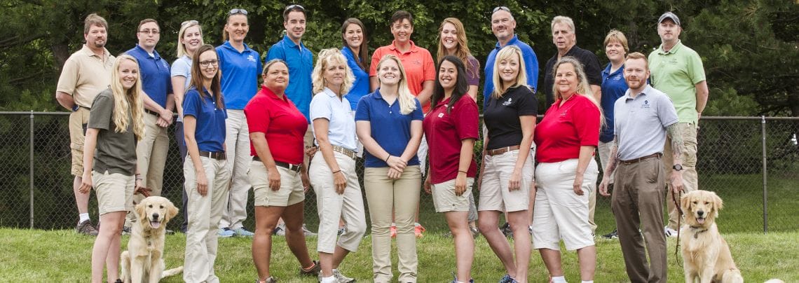 Training-Team-2017 21 male and female Leader Dog guide dog mobility instructors stand in two rows, smiling and facing the camera