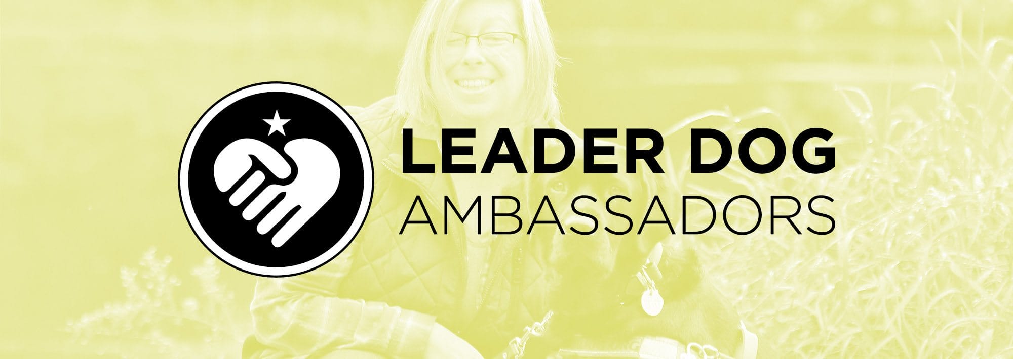 ldb ambassadors Light green colored image of a woman smiling and kneeling next to a black lab in harness. Over the image are the words Leader Dog Ambassadors with a circle icon of folded hands in a heart shape