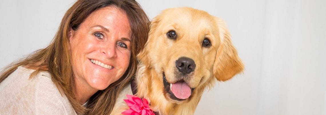 Woman smiling with golden retriever at her side.