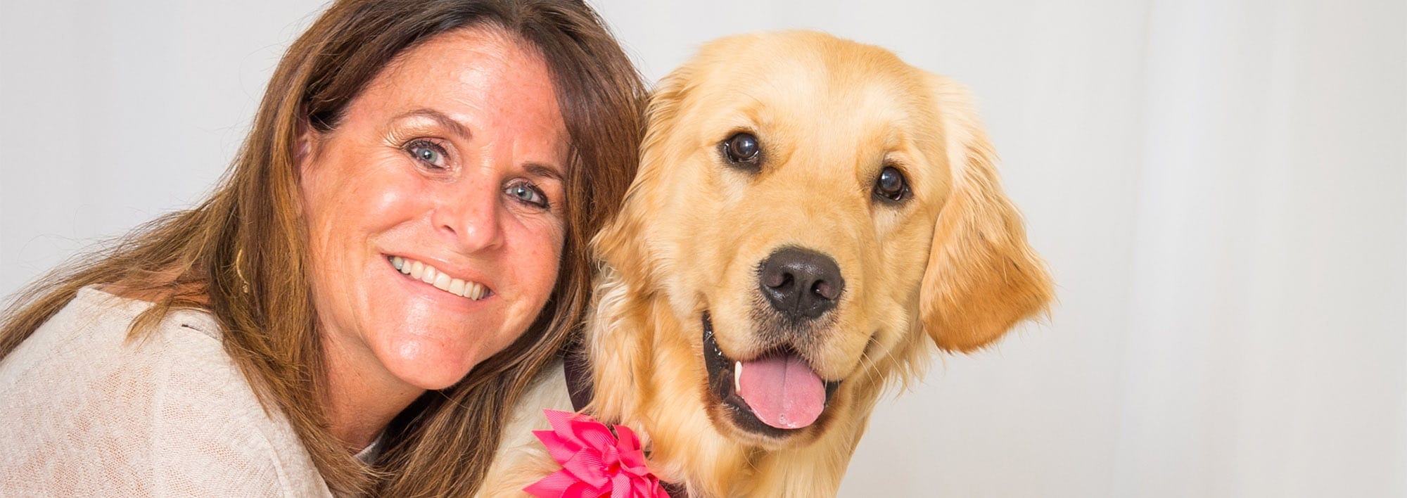 Woman smiling with golden retriever at her side.