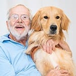 William smiles while hugging golden retriever Brody