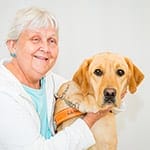 Connie smiles with her arms around yellow lab Sky