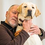 Robert smiles while holding yellow lab Rocky