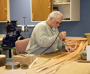 Volunteer Brent works on assembling a harness in the tack shop