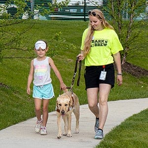 Heidi walks with a young attendee at Leader Dog's Bark & Brew event.
