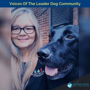 A woman with long blond hair, dark framed glasses and a smile on her face is taking a selfie with a black Labrador retriever next to her. This is Kathy and Laker, a career changed Leader Dog that is well-loved in her home and around the LDB offices.