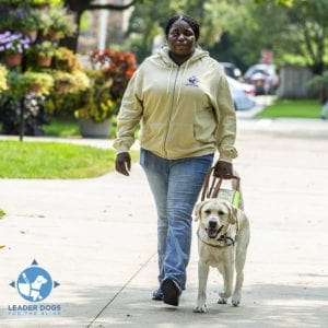 A woman walking with a yellow lab Leader Dog