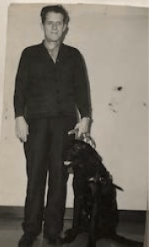 Black and white photo of a man with a black dog