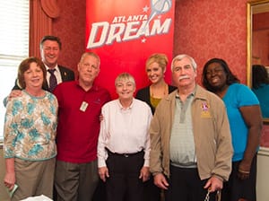 Group of people standing in front of a red "Atlanta Dream" banner