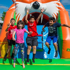 Bark & Brew kids on inflatable A group of kids jump up with smiling faces on an inflatable