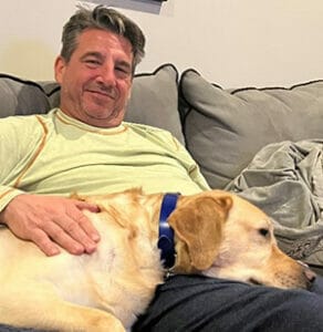 Yellow lab lying its head on smiling man's lap