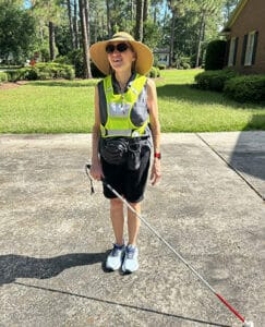 Celia in reflective vest with white cane