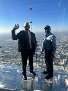 Two men standing in a clear glass box overlooking downtown Chicago