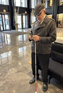 Man with a white cane standing in a lobby