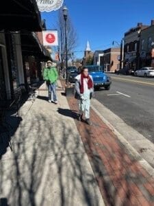 A woman and a man both walking down a sidewalk with their white canes.
