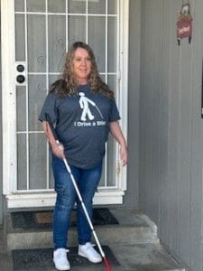 A woman standing with a white cane in front of a doorstep