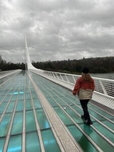 A woman with a white cane walking on the sundial bridge.